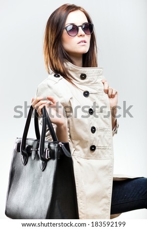 Fashionable woman in white coat with black leather bag