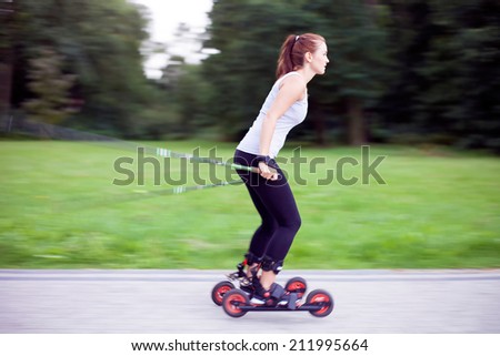 Young woman cross-country skiing with roller ski, park landscape