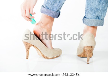Woman in high heels using cosmetics for foot heel