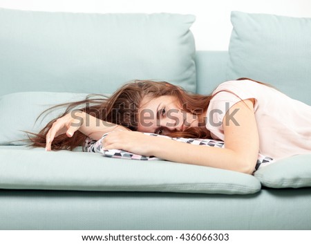 Exhausted young woman lying on couch at home, casual style indoor shoot