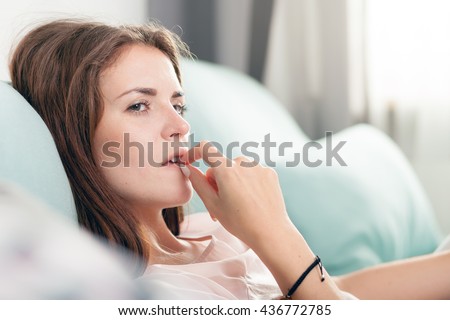 Young woman lying on couch and thinking about something at home, casual style indoor shoot