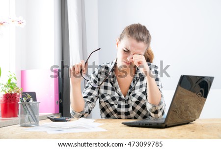 Tired young woman with eye pain during working in home office using laptop