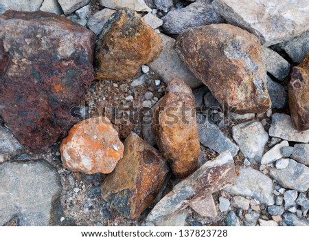 Sulphide red heavy rocks or ore samples in a pile, prospecting for gold in Norway.