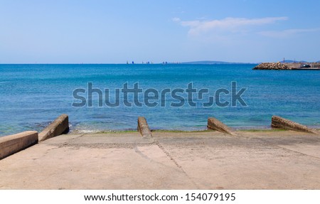Launch area and sailing regatta with white and blue sails across Palma Bay, Majorca, Spain.
