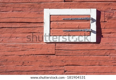 Red Log House Wall with Hatch. Detail of traditional Swedish red painted log house with white painted trimmings around the hatch. Stockholm, Sweden.