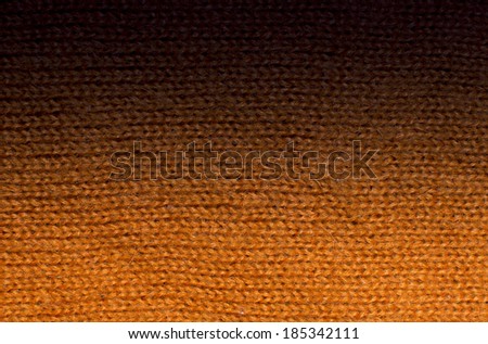 Orange wool knit work fade to black. Orange wool knit work full frame for warming backdrop or background.