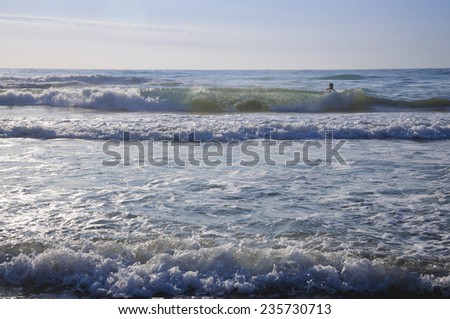 TORREVIEJA, COSTA BLANCA, SPAIN ON JULY 24 2012: Young man swims in wild waves on a Mediterranean beach on a sunny summer morning on July 24 2012 in Torrevieja, Costa Blanca, Spain.