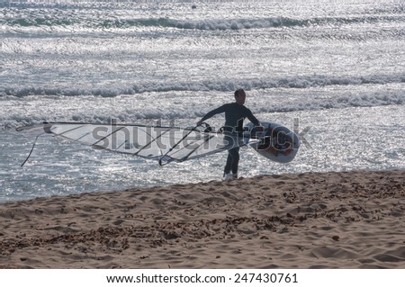 CAN PASTILLA, MAJORCA, SPAIN - FEBRUARY 10 2013: Wind surfer with his board on his way up on a sunny winter beach on February 10, 2013 in Can Pastilla, Majorca, Spain.