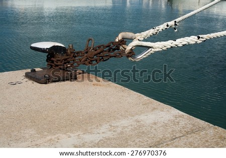 Industrial rusty mooring chain and knob closeup on jetty with water. Mallorca, Balearic islands, Spain.