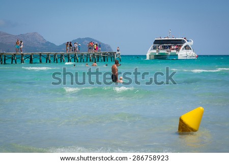 PLAYA DE MURO, MALLORCA, SPAIN - JULY 15, 2014: Catamaran by the jetty, dad with boy in the water on July 15, 2014 in Playa de Muro, Mallorca, Balearic islands, Spain.