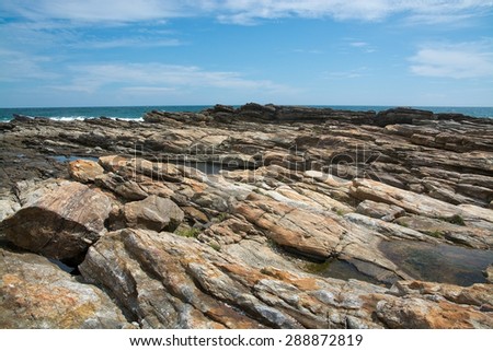 Rocky coast landscape with metamorphic rocks and splashing foaming waves, Southern Province, Sri Lanka, Asia.