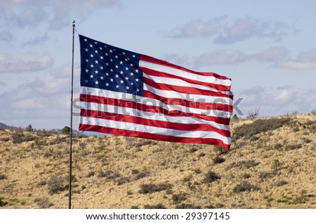 Close-up of a US flag blowing in a strong wind over high desert terrain in northern Arizona.