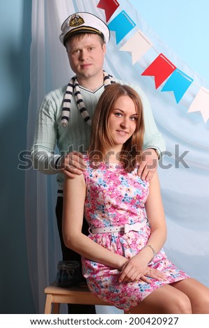 Beautiful smiling woman and man pose in studio with marine decorations