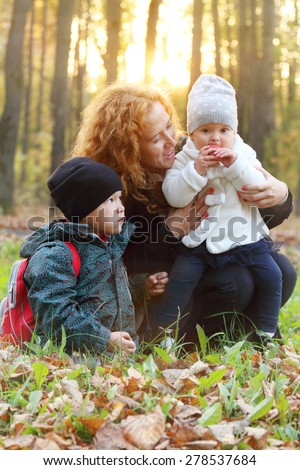 Woman with little daughter and son pose in autumn park at evening