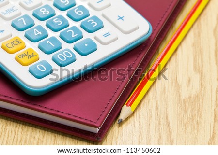 Office book with a pencil and a calculator on a office table.