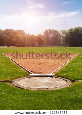 Shot put field with sun and trees in background