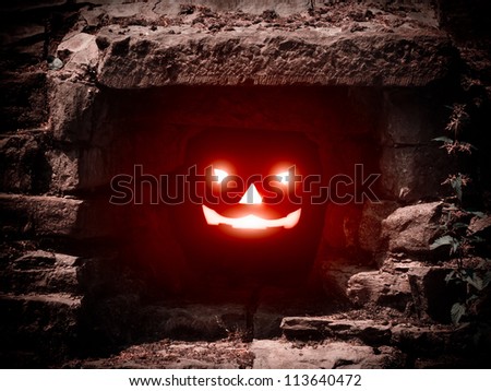 Halloween concept with lit pumpkin in dark cave