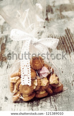 Bag with iced gem biscuits on wooden table