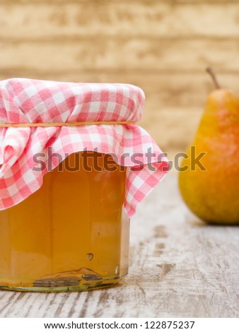 Homemade pear jelly in jar with piece of fruit on wooden table