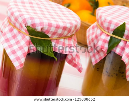 Homemade tricolor jam in jars with fruit basket in background