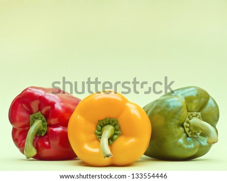 Red, yellow and green pepper on green background