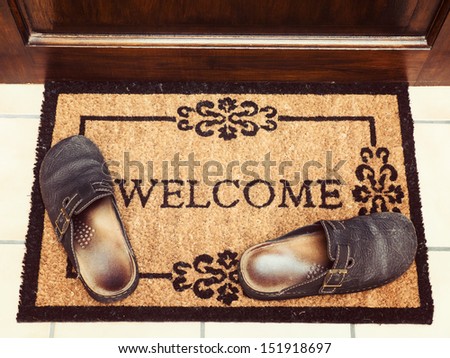 Welcome mat with leather slippers at door, vintage toned