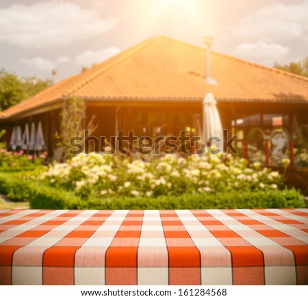 Red checkered tablecloth outdoors against restaurant background