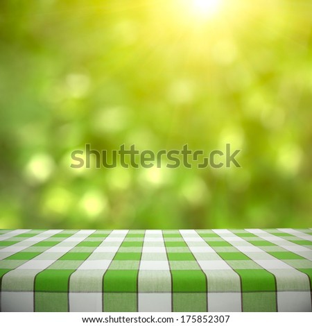 Empty picnic table on green foliage bokeh background