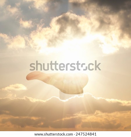 Hand of god holding sun in cloudy sky