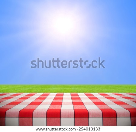 Picnic table in grass field against clear blue sky with sun