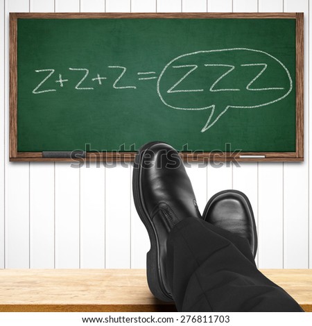 Boring class or bored teacher concept with feet on table against zzz written on chalkboard