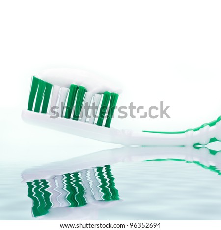Fresh green toothbrush on white with water in foreground