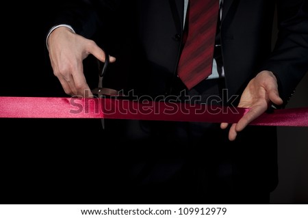 man in a suit, cuts a red tape, opening of event