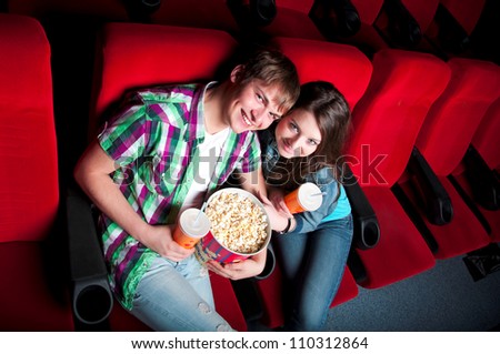 young couple in a movie theater, hugging and happy to have a good time together