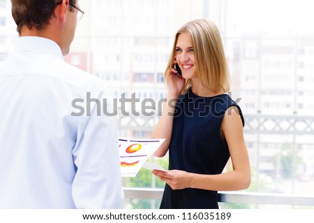 business male and business female discuss reports, Woman talking on cell phone