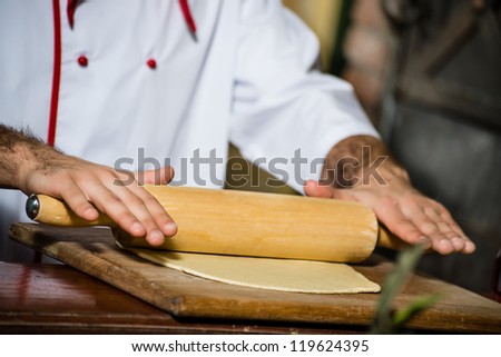 cook man rolls the dough with a rolling pin, for pizzas