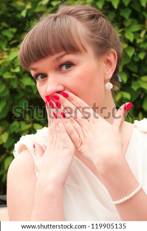 Portrait of a surprised young woman with hands over her mouth