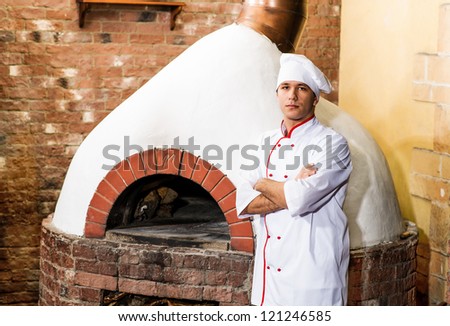 portrait of a cook in the kitchen near the wood-burning oven for pizzas, traditional cuisine