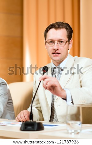 Portrait of a business man holding a microphone and looks ahead