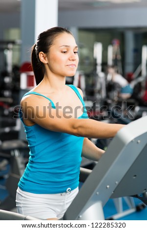 attractive young woman adjusts the treadmill at the beginning of training, do fitness in the sport club