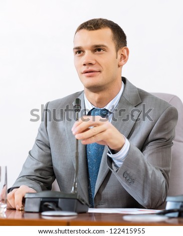 Portrait of a businessman, said into the microphone, the meeting