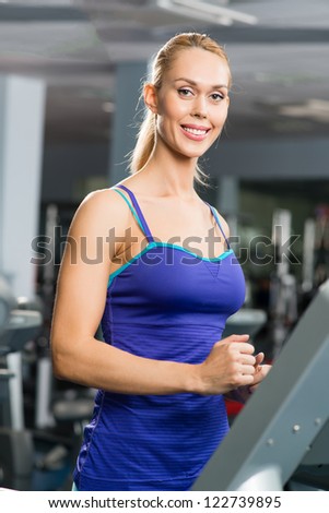 attractive young woman runs on a treadmill, is engaged in fitness sport club