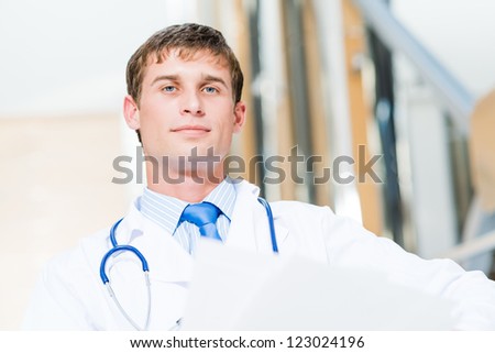 Portrait of a doctor holding papers in hand, office space