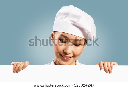 female chef holding a poster for text, look at the poster and smiling