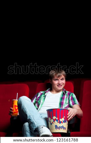 man in a movie theater, watching a movie and drink a drink
