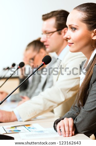 businessmen communicate at the conference, sitting at the table, on the table microphones and documents