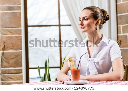 portrait of a nice lady in a restaurant, sitting with one cocktail at the table and waiting