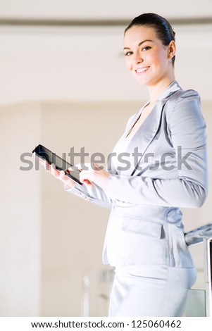 Portrait of a business woman in the tablet at the office, turned around and looking at the camera