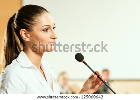 Portrait of a business woman holding a microphone and looks ahead
