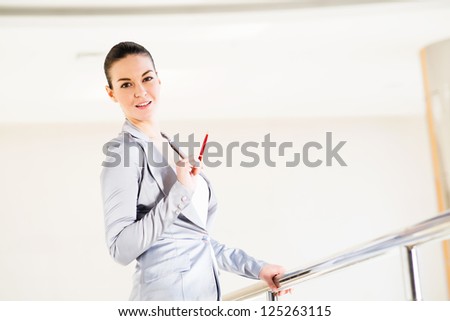 Business woman standing in the lobby of the office, based on the railing of the balcony